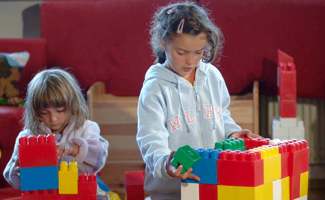 Two girls play in the playroom with large blocks of lego